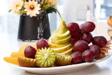 Sliced ​​fruits on a white plate on a table in a cafe