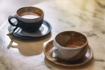 Closeup image of two cups of hot coffee on marble table in cafe