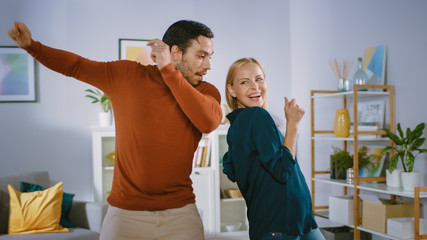 Beautiful Happy Young Couple in Love Dancing in the Middle of the Living Room. Boyfriend and...