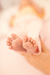 Obraz na płótnie Canvas Mother holding her baby's feet on bed, closeup