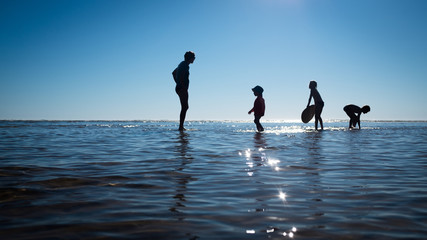 Fototapeta premium Silhouettes mère et enfants dans l'eau - Mother and children silhouettes in the water