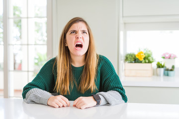 Young beautiful plus size woman wearing casual striped sweater angry and mad screaming frustrated and furious, shouting with anger. Rage and aggressive concept.