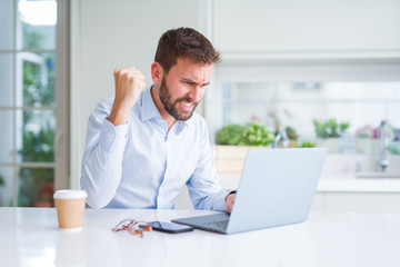 Handsome man working using computer laptop and drinking a cup of coffee annoyed and frustrated shouting with anger, crazy and yelling with raised hand, anger concept
