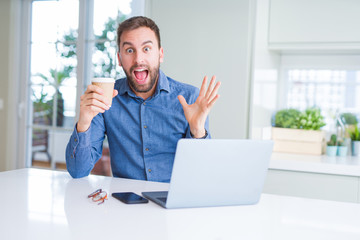 Handsome man working using computer laptop and drinking a cup of coffee very happy and excited, winner expression celebrating victory screaming with big smile and raised hands