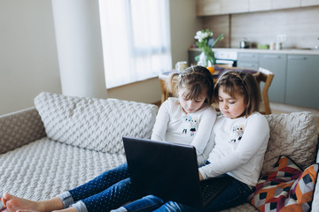 Young teen girls together gaming, chatting, watching videos, listening to music on laptop at home. Leisure, lifestyle, technology, new generation concept