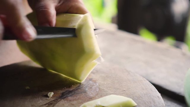 Old lady using knife to cut a winter melon to pieces. Ingredient for cooking