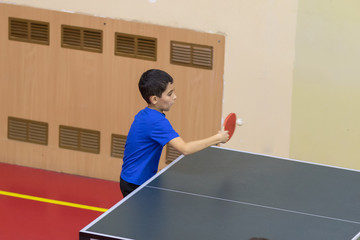The boy playing table tennis in blue t-shirt