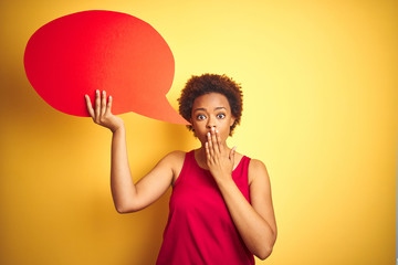 Young african american woman holding speech bubble over yellow isolated background cover mouth with hand shocked with shame for mistake, expression of fear, scared in silence, secret concept