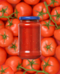 Envase con salsa de tomate con tomates naturales de fondo