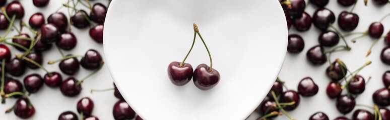 panoramic shot of fresh, sweet and red cherries on white plate