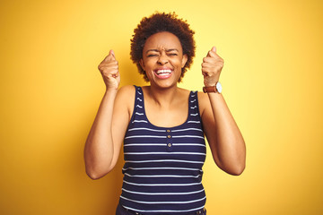 Beauitul african american woman wearing summer t-shirt over isolated yellow background excited for success with arms raised and eyes closed celebrating victory smiling. Winner concept.