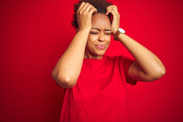 Young beautiful african american woman with afro hair over isolated red background suffering from headache desperate and stressed because pain and migraine. Hands on head.