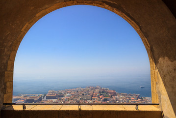 Panoramic view of the city of Naples through the arch of the medieval fortress Castel Sant'Elmo. Skyline and Gulf of Naples, Campania region, Italy.