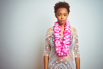 Young african american woman with afro hair wearing flower hawaiian lei over isolated background...