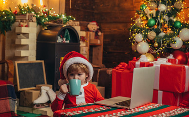 Boy child with laptop near christmas tree. Buy christmas gifts online. Christmas shopping concept....