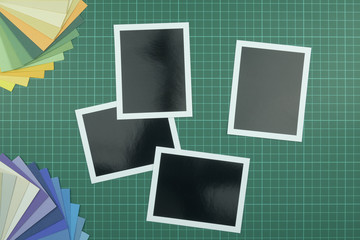 Top down view of blank photographs on cutting mat with colour swatch in the corner