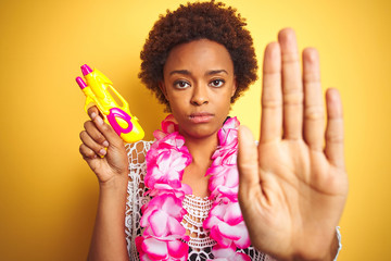 Young african american woman with afro hair wearing flower hawaiian lei and water gun with open...