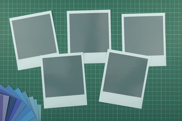 Top down view of blank instant film style photographs on cutting mat with colour swatch in the corner