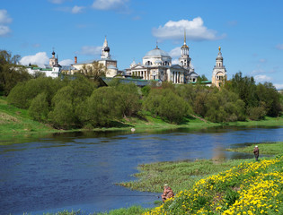 View of Novotorzhsky Borisoglebsky Monastery and Tvertsa river with fishermen in the foreground. Tver region, Russia. Sunny spring day