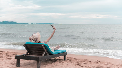 Traveller woman selfie on the beach chair, summer beach vacation concept.