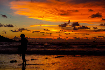 People are playing at the beach and waiting to watch the sunset.