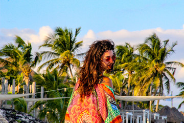 Girl walking on white sandy beach with palm trees in Tulum, Mexico