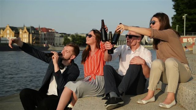 Group Of Students Doing Selfie Over the University Building. Four Young Happy Students Making Selfie and Smiling Outdoors. Friends Having a Lot of Fun Spending Time Together and Drinking Beer.