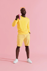 Fototapeta na wymiar Drink. Happy black man in yellow fashion clothes with soft drink