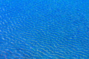 Ripples on the surface of the water with sun glare. Blue water.