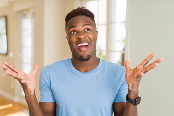 Handsome african american man wearing casual t-shirt celebrating mad and crazy for success with arms raised and closed eyes screaming excited. Winner concept