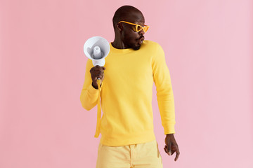 Black man in fashion clothes with megaphone on pink background