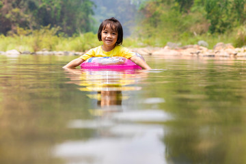 Fototapeta na wymiar Little Asian girl with pool ring floating in river