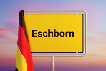 Eschborn. Gelbes Schild/Ortsschild. Flagge von Deutschland hängt darüber. Himmel mit Sonnenuntergang oder Sonnenaufgang