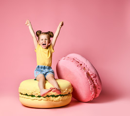 Cute little girl in bright clothes have fun at the birthday party fun room decoration candy macarons © FAB.1