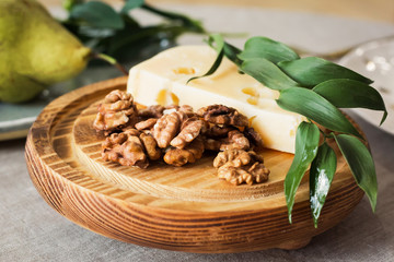 olivy  hard cheese with walnuts lies on a wooden board with a sprig of olive
