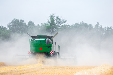 The machine for harvesting grain crops - combine harvester in action on rye field at sunny summer...