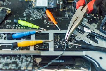 a man repairs a computer, solders a board, repairs electronics and modern technologies
