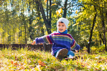 boy in sweater and hat sitting on the grass