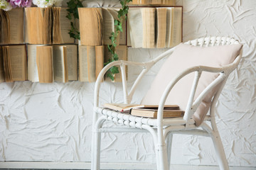 Obraz na płótnie Canvas Wicker chair with a pillow and books