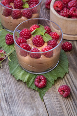 fresh raspberry with chocolate mousse in glass glasses on wooden background