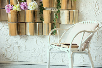 Obraz na płótnie Canvas Wicker chair with a pillow and books.
