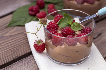 fresh raspberry with chocolate mousse in glass glasses on wooden background