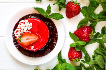 Juicy tasty strawberry jam souffle on a white wooden background decorated with fresh strawberries and beautiful green mint berries
