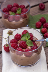 fresh raspberry with chocolate mousse in glass glasses on wooden background