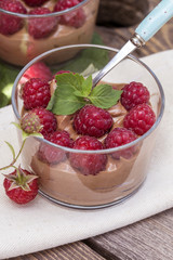 fresh raspberry with chocolate mousse in glass glasses on wooden background