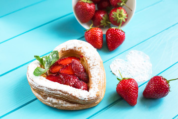 Heart-shaped cake with strawberries and mint on a bright blue background