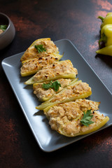 Roasted peppers stuffed with cheese and herbs on a gray plate. Characteristic dish of the Balkan cuisine. Serbian cuisine. On a dark rustic background, close-up, selective focus