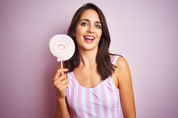 Young beautiful woman eating sweet candy over pink isolated background with a happy face standing and smiling with a confident smile showing teeth