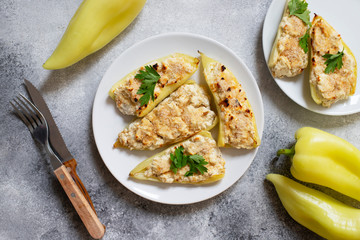 Roasted peppers stuffed with cheese and herbs on a white plate. Characteristic dish of the Balkan cuisine. Serbian cuisine. Gray background, top view, copy space
