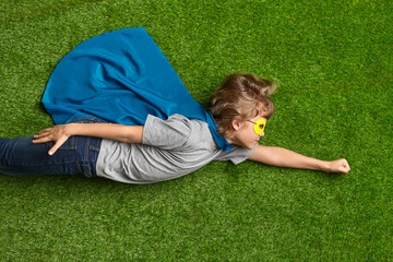 Little superhero flying over grass